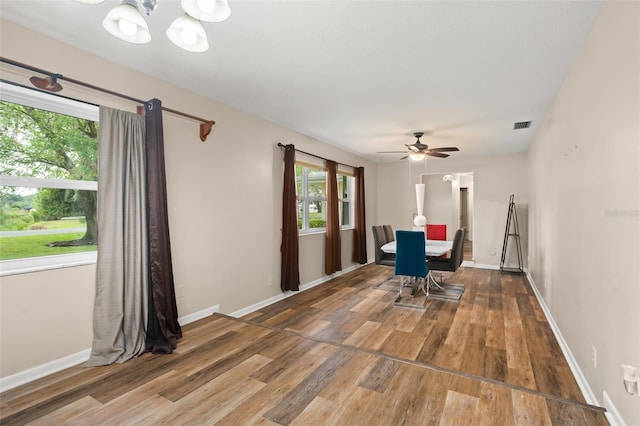 unfurnished dining area featuring ceiling fan with notable chandelier, wood finished floors, and baseboards