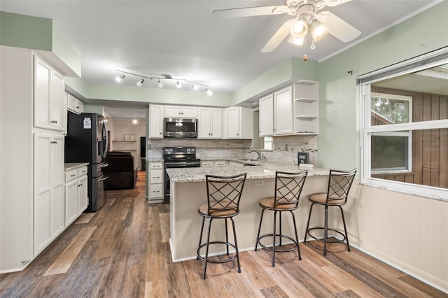 kitchen featuring a sink, a peninsula, white cabinets, and stainless steel appliances