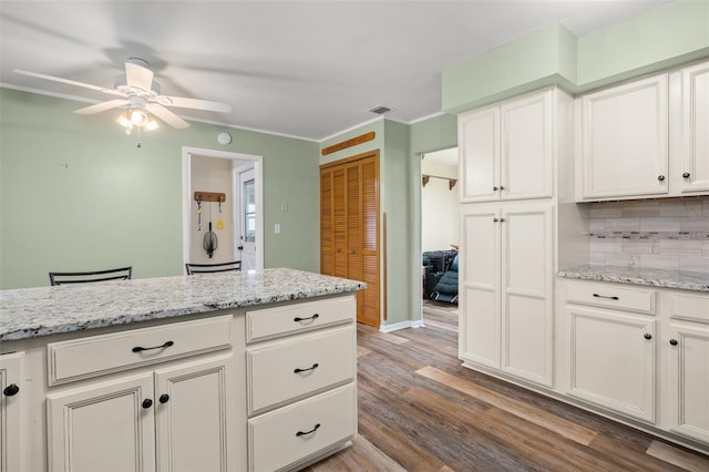 kitchen featuring visible vents, white cabinetry, light wood finished floors, decorative backsplash, and ceiling fan