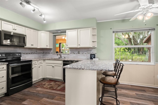 kitchen featuring dark wood-type flooring, a kitchen breakfast bar, a peninsula, and stainless steel appliances