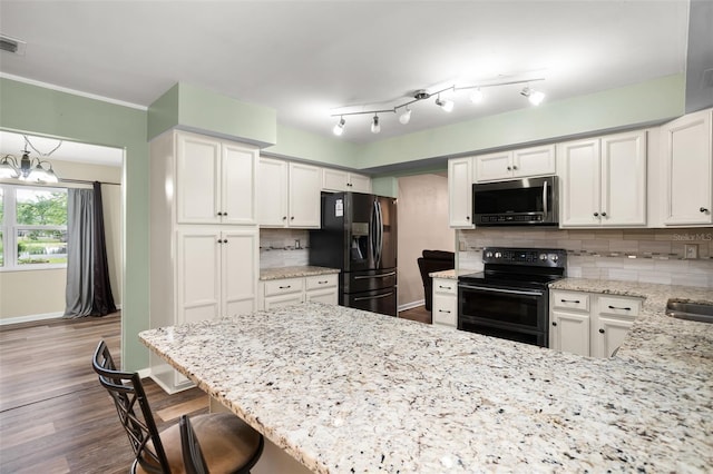 kitchen with light stone counters, dark wood-style floors, baseboards, black appliances, and backsplash