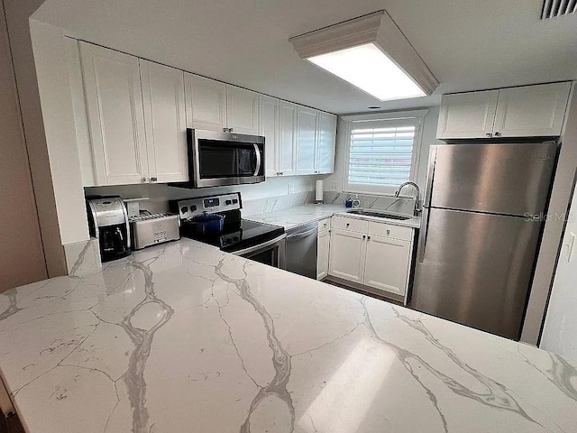 kitchen featuring visible vents, appliances with stainless steel finishes, white cabinetry, and a sink