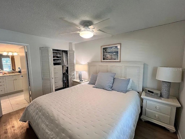 bedroom featuring wood finished floors, ceiling fan, a closet, a textured ceiling, and connected bathroom