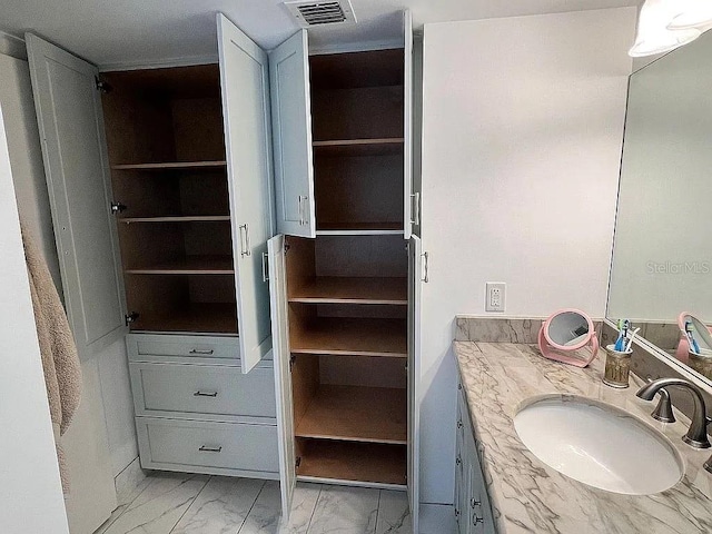 bathroom featuring a spacious closet, visible vents, marble finish floor, and vanity