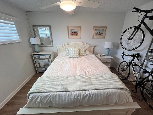 bedroom featuring ceiling fan, a textured ceiling, baseboards, and dark wood-style flooring