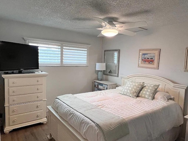 bedroom with ceiling fan, dark wood-style floors, and a textured ceiling