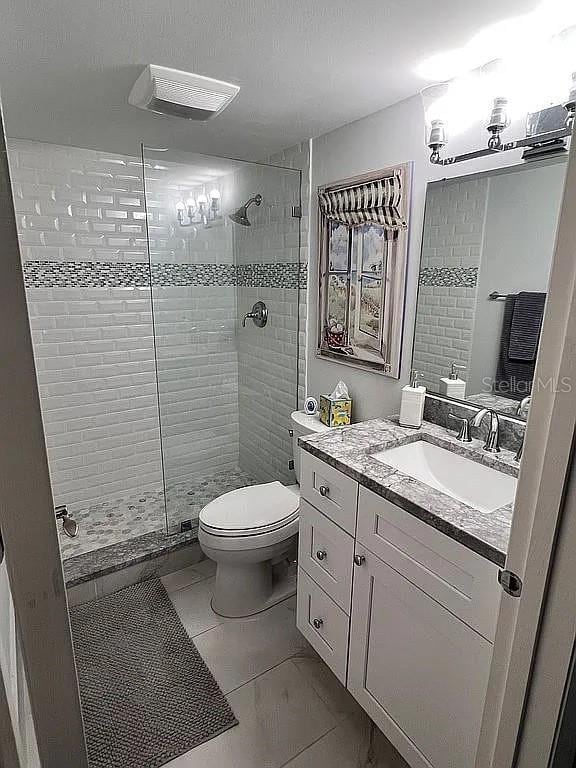 bathroom featuring vanity, toilet, visible vents, and a tile shower