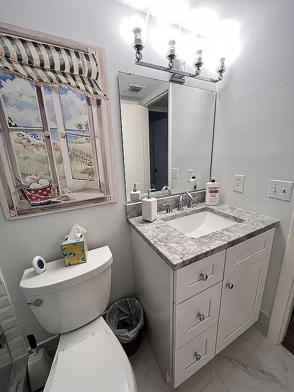 bathroom featuring visible vents, toilet, marble finish floor, and vanity