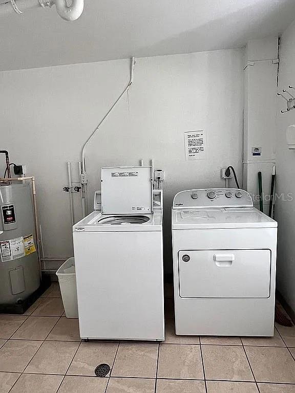 washroom featuring washer and dryer, light tile patterned floors, and electric water heater