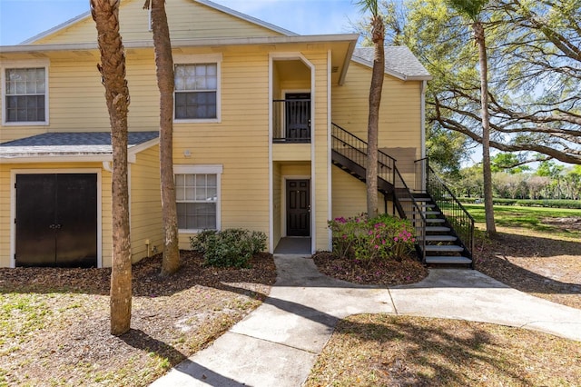 townhome / multi-family property featuring stairway and roof with shingles