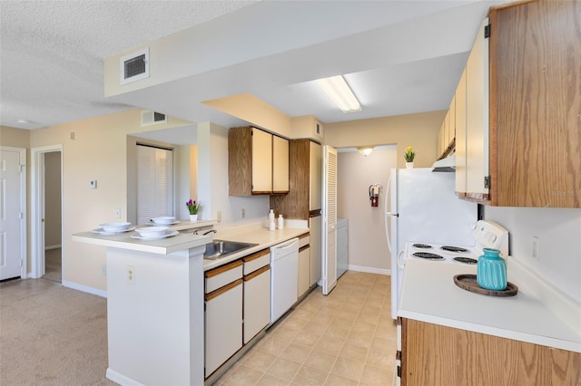 kitchen with visible vents, light countertops, a peninsula, white dishwasher, and a sink