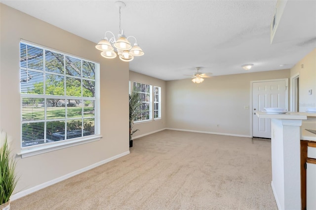 interior space with a textured ceiling, baseboards, light colored carpet, and ceiling fan with notable chandelier