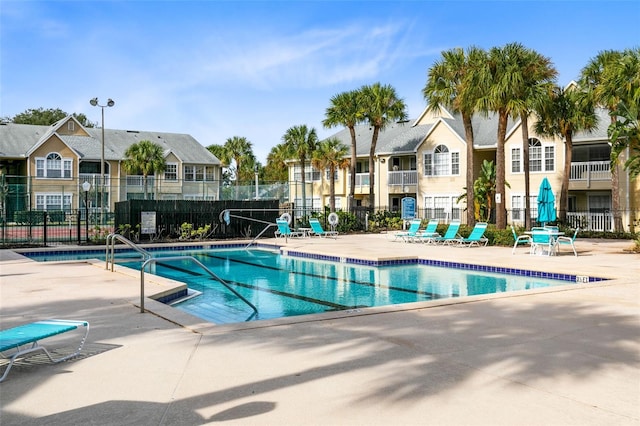 community pool featuring a residential view, a patio, and fence