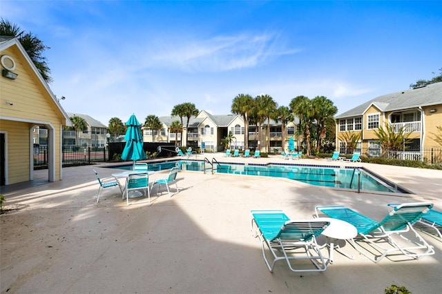community pool featuring a patio, fence, and a residential view