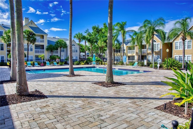 pool with a patio area, fence, and a residential view