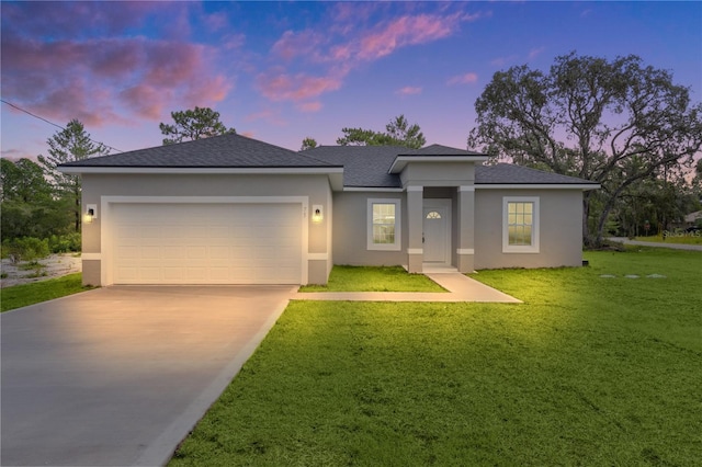 view of front facade with stucco siding, a lawn, concrete driveway, and an attached garage