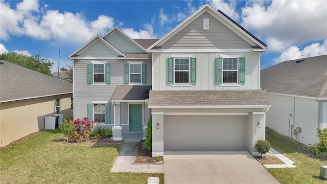 craftsman-style home with a front yard, roof with shingles, concrete driveway, and an attached garage