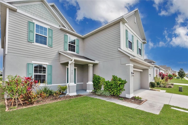 view of front facade featuring a front yard, an attached garage, driveway, and stucco siding