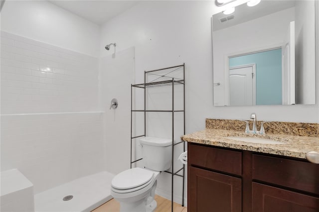 bathroom with vanity, toilet, visible vents, and tiled shower