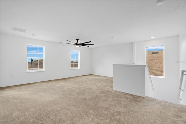 empty room with visible vents, light colored carpet, and ceiling fan