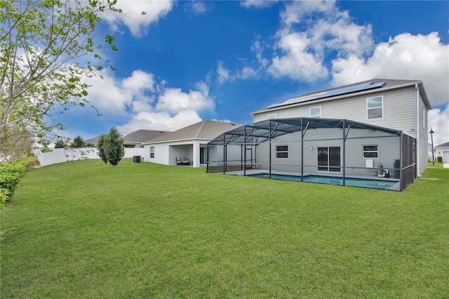 back of house featuring an outdoor pool, glass enclosure, a lawn, and a patio area