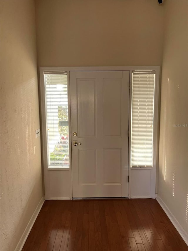 entryway with dark wood finished floors, baseboards, and a textured wall