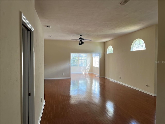 unfurnished room featuring visible vents, dark wood-type flooring, a textured ceiling, baseboards, and ceiling fan