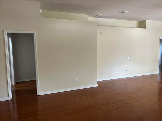 unfurnished room with visible vents, baseboards, and dark wood-type flooring