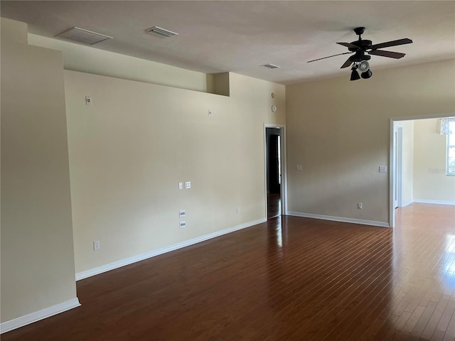 spare room featuring baseboards, visible vents, dark wood-style flooring, and ceiling fan