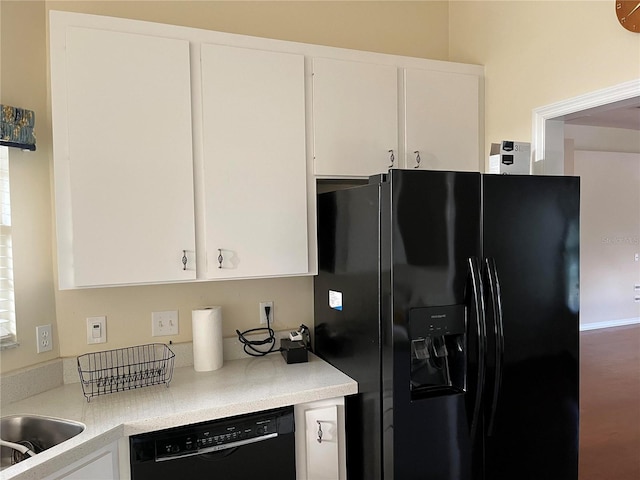 kitchen with white cabinets, black appliances, light countertops, and a sink