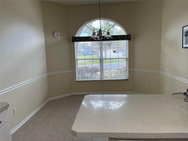 spare room featuring light tile patterned flooring, a notable chandelier, and baseboards