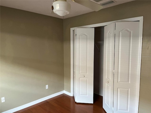 unfurnished bedroom with a closet, visible vents, dark wood-type flooring, and baseboards