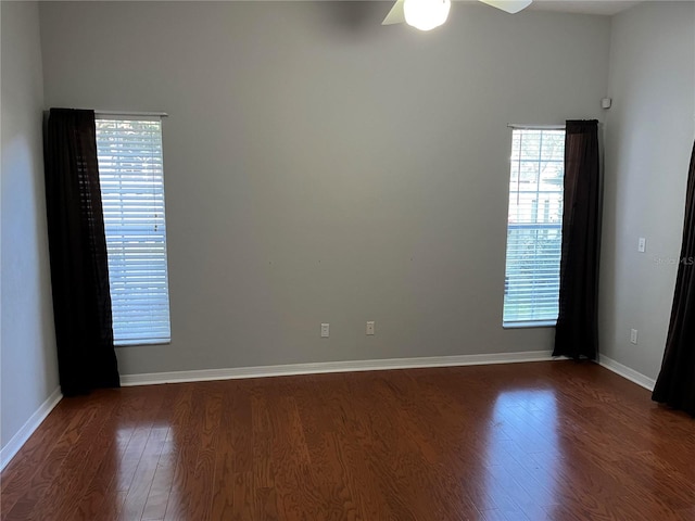 empty room featuring wood finished floors, baseboards, and ceiling fan