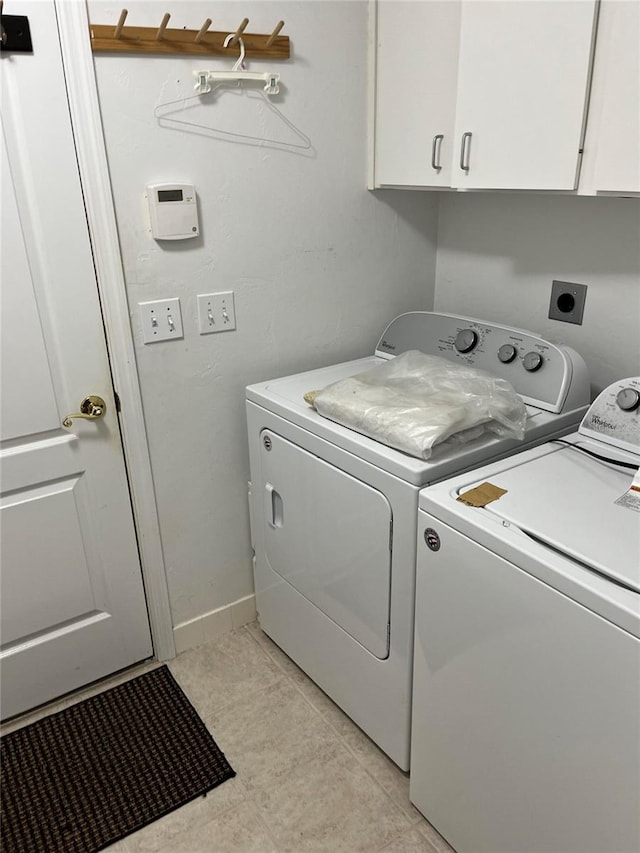 laundry area with light tile patterned floors, cabinet space, and washer and clothes dryer