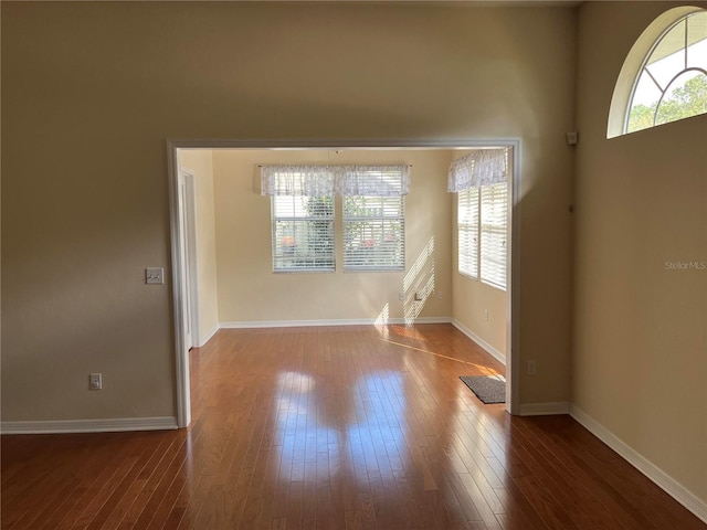 unfurnished room with baseboards and hardwood / wood-style flooring