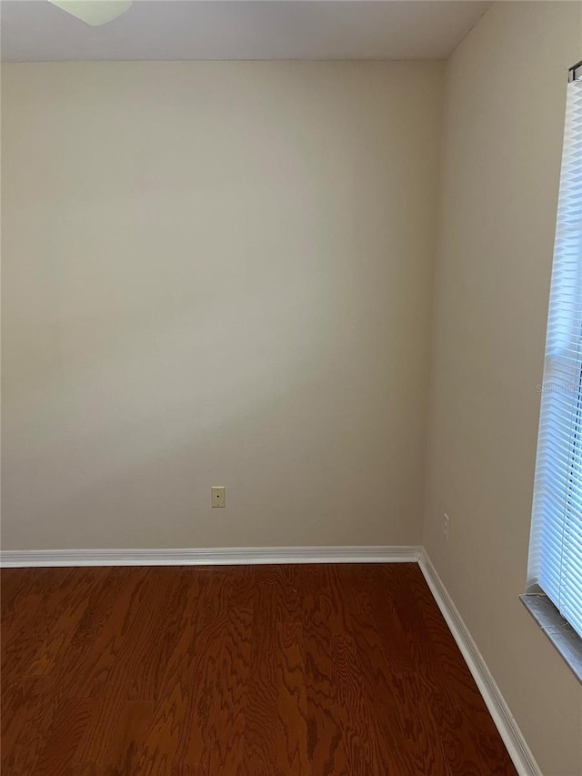 unfurnished room with baseboards and dark wood-style floors
