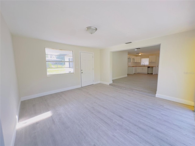 unfurnished living room with baseboards and light wood-type flooring