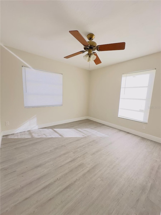 spare room featuring a ceiling fan, light wood-style floors, and baseboards