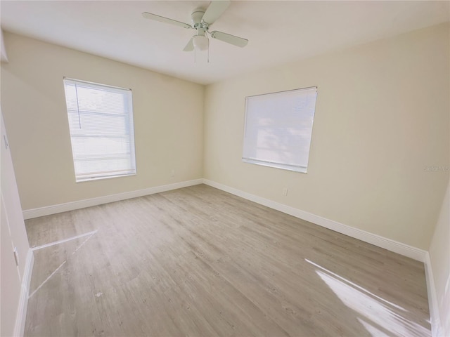 spare room featuring baseboards, wood finished floors, and a ceiling fan