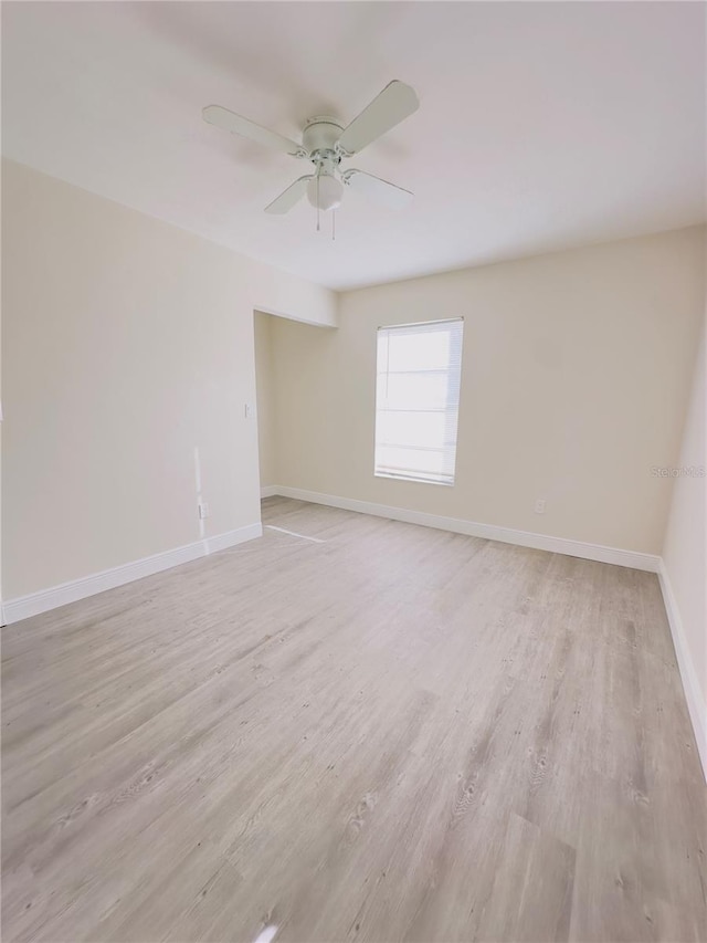 spare room with ceiling fan, baseboards, and light wood-style flooring