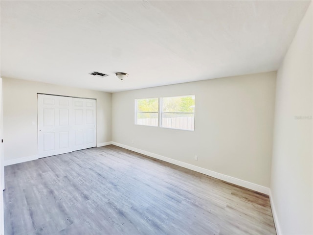 unfurnished bedroom featuring a closet, baseboards, and wood finished floors