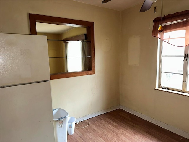 empty room featuring wood finished floors, a ceiling fan, and baseboards