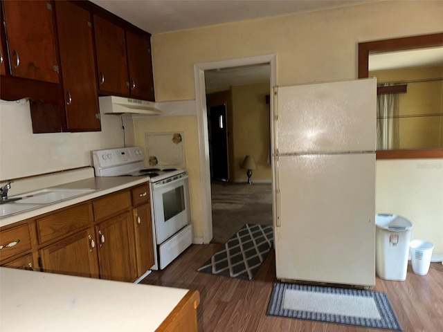 kitchen with white appliances, dark wood-style flooring, a sink, light countertops, and under cabinet range hood