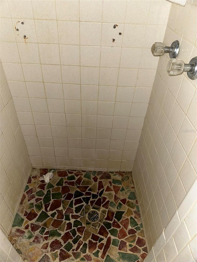 bathroom with stone finish floor and a tile shower