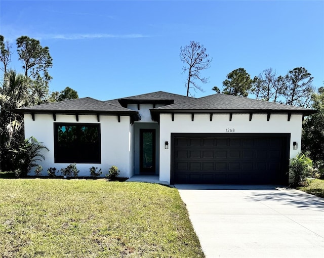 prairie-style home featuring a shingled roof, a front lawn, stucco siding, driveway, and an attached garage