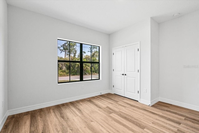 unfurnished bedroom with baseboards, light wood-type flooring, and a closet