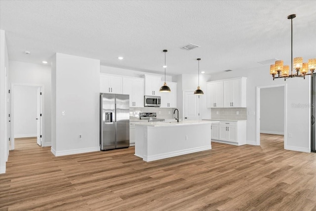 kitchen featuring light wood finished floors, visible vents, light countertops, a notable chandelier, and stainless steel appliances