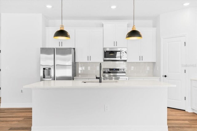 kitchen with light wood-style flooring, an island with sink, a sink, stainless steel appliances, and white cabinetry