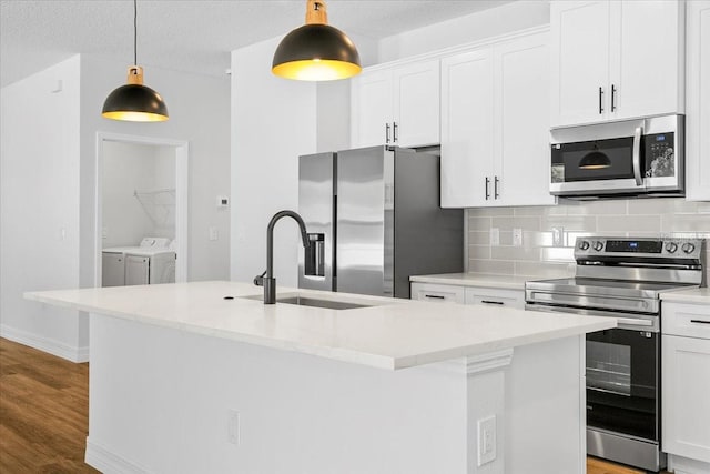 kitchen featuring wood finished floors, a sink, decorative backsplash, appliances with stainless steel finishes, and independent washer and dryer