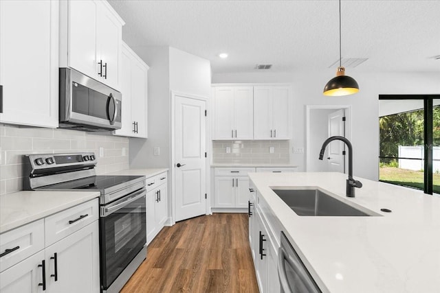 kitchen with visible vents, a sink, light countertops, appliances with stainless steel finishes, and dark wood-style flooring